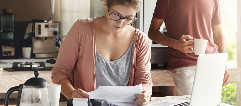 Jonge vrouw betaald een factuur achter de computer