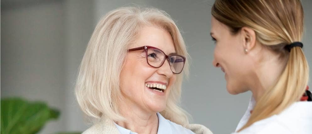 Dame van middelbare leeftijd lachend in gesprek met haar dochter