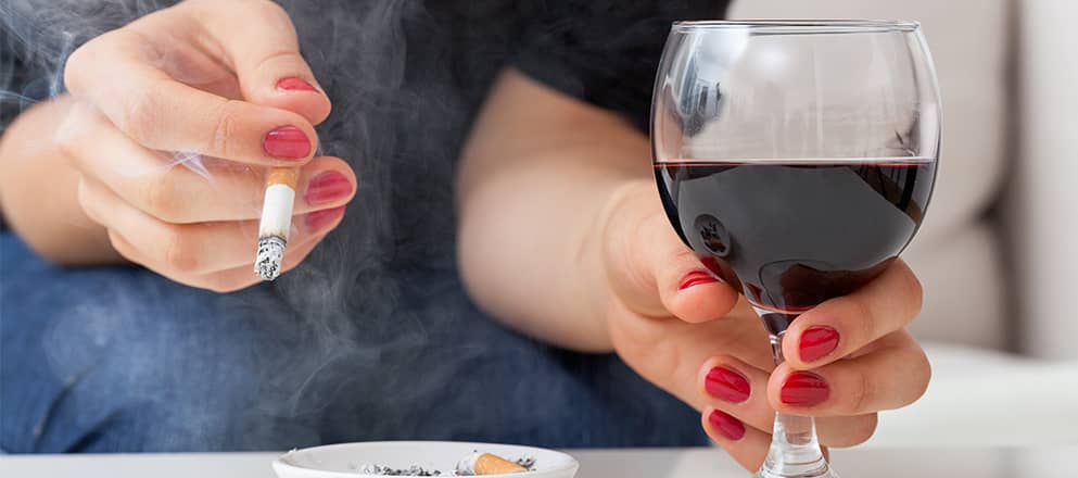 Een vrouw met een sigaret en een glas wijn in haar handen