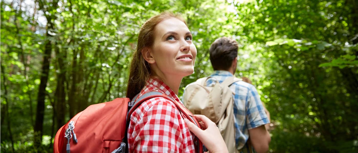 Jonge vrouw loopt met backpack door het bos.
