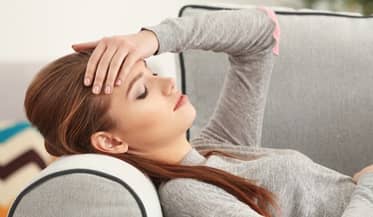 Vrouw met migraine ligt op de bank