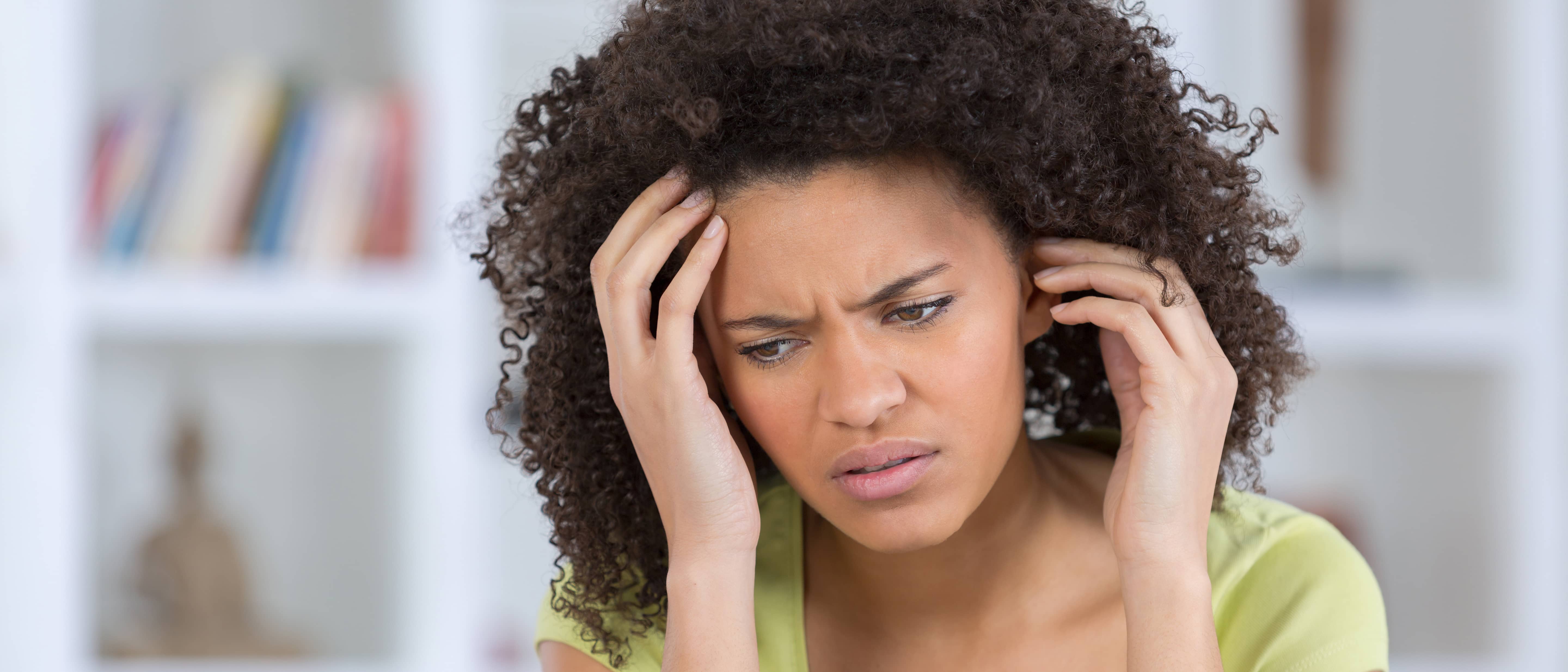 Een jonge vrouw grijpt naar haar hoofd vanwege de hoofdpijn