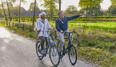 Oudere vrouw en man op de fiets