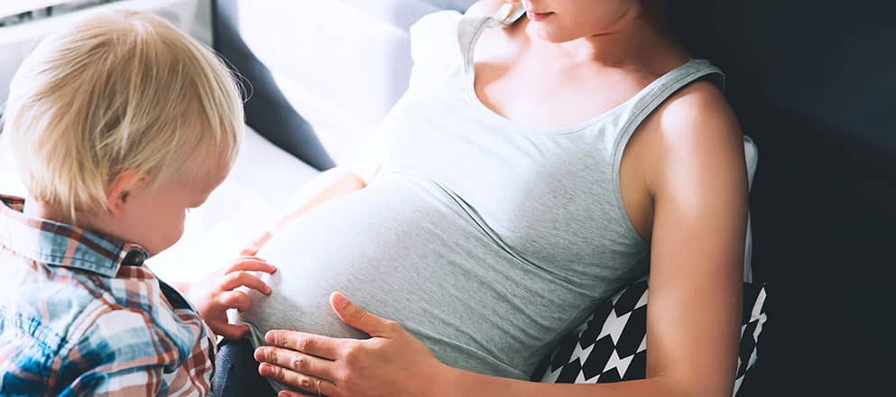 Een vrouw met haar zoontje wrijven over de zwangere buik