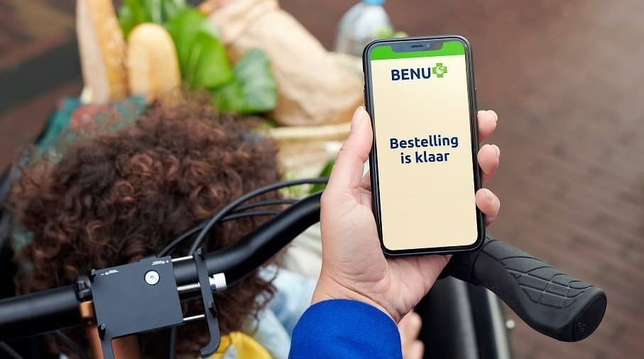 Persoon houdt telefoon vast met BENU herhaalservice-app