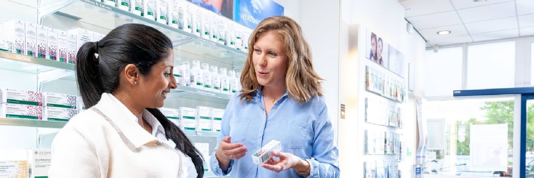 Klant met apotheker bij schap met zelfzorg producten